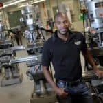 Montez King, an instructor at Magna Baltimore Technical Training Center, stands near machines at the Baltimore school Friday, June 29, 2012. (Photo by Steve Ruark)